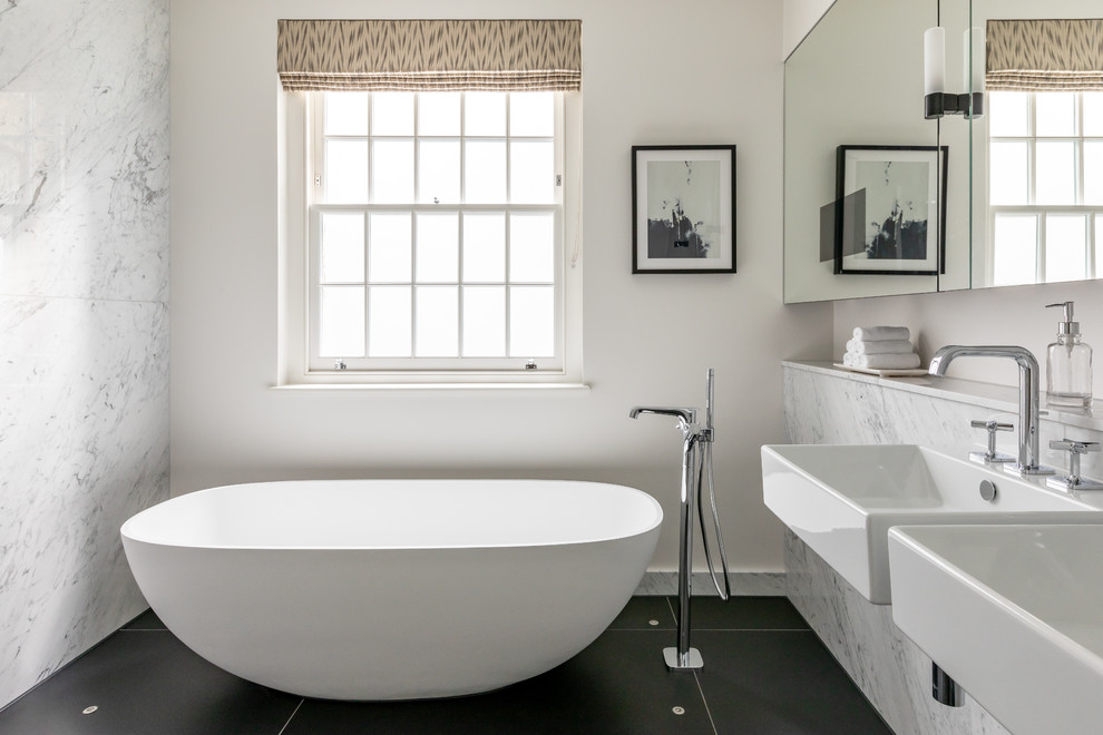 Ejemplo de cuarto de baño principal contemporáneo con bañera exenta, baldosas y/o azulejos blancos, baldosas y/o azulejos de mármol, paredes blancas, lavabo suspendido, suelo negro y espejo con luz