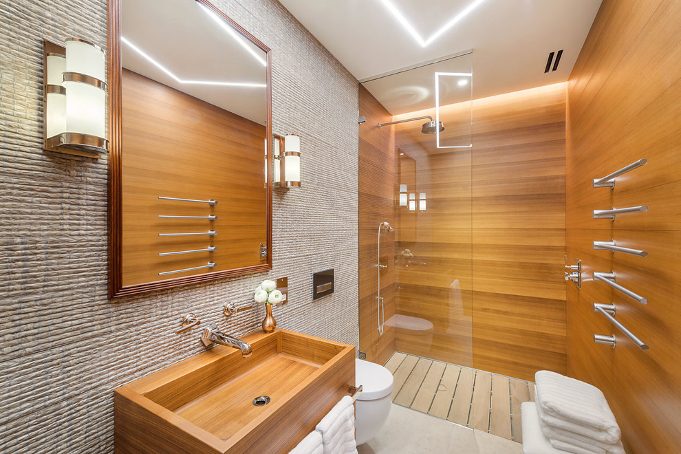 Inredning av ett exotiskt stort en-suite badrum, med släta luckor, vita skåp, en öppen dusch, en vägghängd toalettstol, marmorkakel, ett väggmonterat handfat, träbänkskiva, med dusch som är öppen och beige väggar