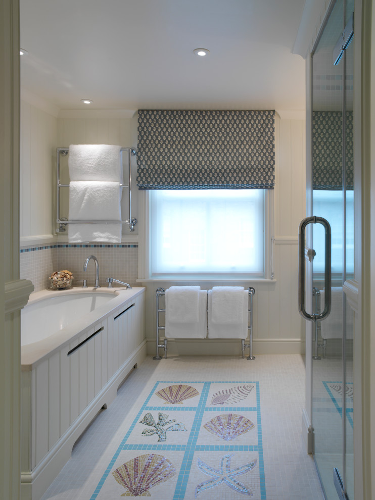 Cette image montre une salle de bain marine avec une baignoire encastrée, un carrelage multicolore, mosaïque et un mur beige.