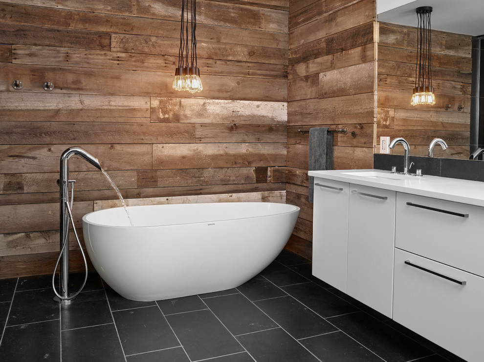 Modern inredning av ett mellanstort badrum, med släta luckor, vita skåp, granitbänkskiva, ett fristående badkar, grå kakel och ett undermonterad handfat