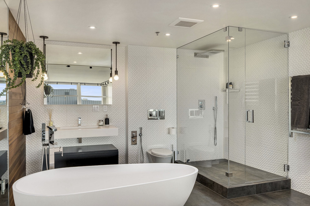 This is an example of a medium sized contemporary ensuite bathroom in Seattle with white cabinets, a corner shower, a wall mounted toilet, white tiles, a submerged sink, grey floors, a hinged door, white worktops, a single sink, a floating vanity unit and flat-panel cabinets.