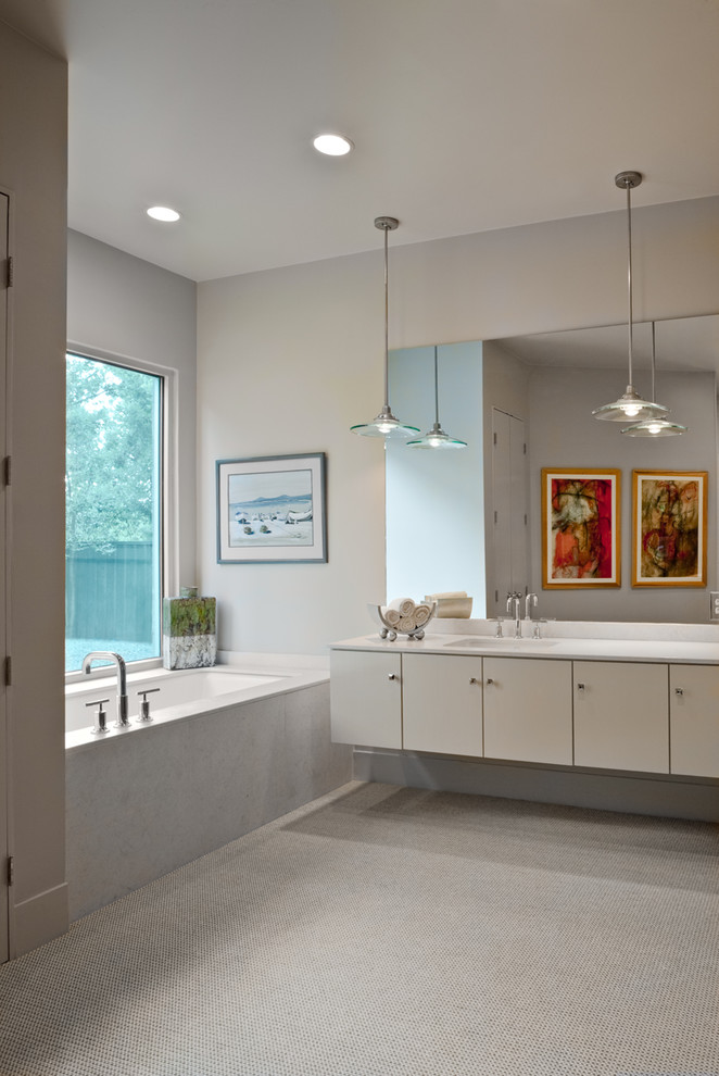 Diseño de cuarto de baño principal actual con lavabo bajoencimera, armarios con paneles lisos, puertas de armario grises, bañera encastrada sin remate, baldosas y/o azulejos grises y paredes grises