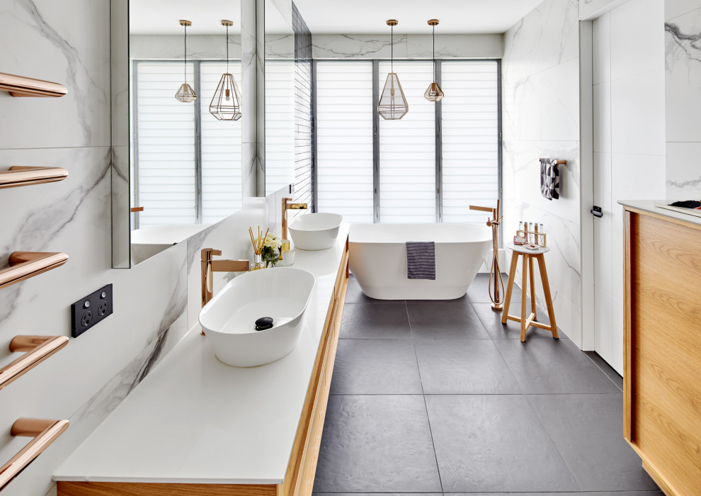 Exempel på ett mycket stort modernt vit vitt en-suite badrum, med släta luckor, beige skåp, ett fristående badkar, grå kakel, porslinskakel, klinkergolv i porslin, ett fristående handfat, bänkskiva i akrylsten och grått golv