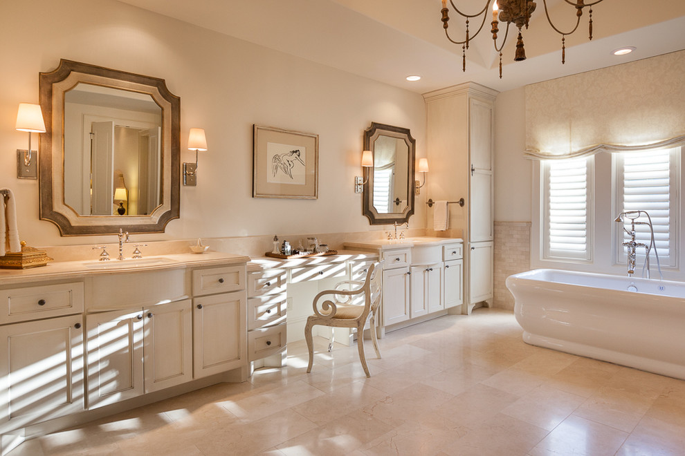 Ejemplo de cuarto de baño principal clásico grande con armarios con paneles empotrados, puertas de armario blancas, encimera de mármol, bañera exenta y baldosas y/o azulejos beige