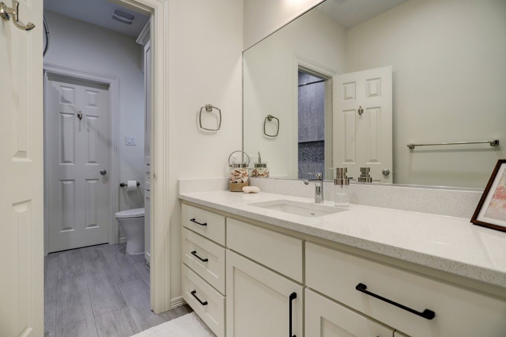 Inspiration for a medium sized classic family bathroom in Houston with shaker cabinets, white cabinets, an alcove bath, a shower/bath combination, a one-piece toilet, grey tiles, cement tiles, white walls, ceramic flooring, a built-in sink, quartz worktops, grey floors, a shower curtain, white worktops, a wall niche, a single sink and a built in vanity unit.
