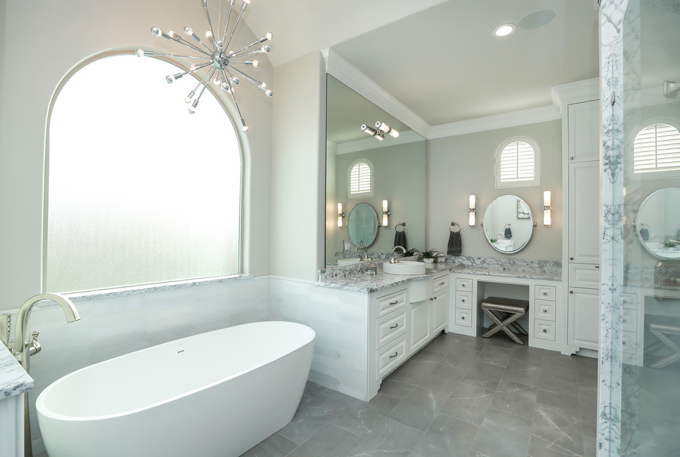 Пример оригинального дизайна: огромная главная ванная комната в стиле неоклассика (современная классика) с фасадами с выступающей филенкой, белыми фасадами, отдельно стоящей ванной, двойным душем, настольной раковиной, мраморной столешницей и открытым душем