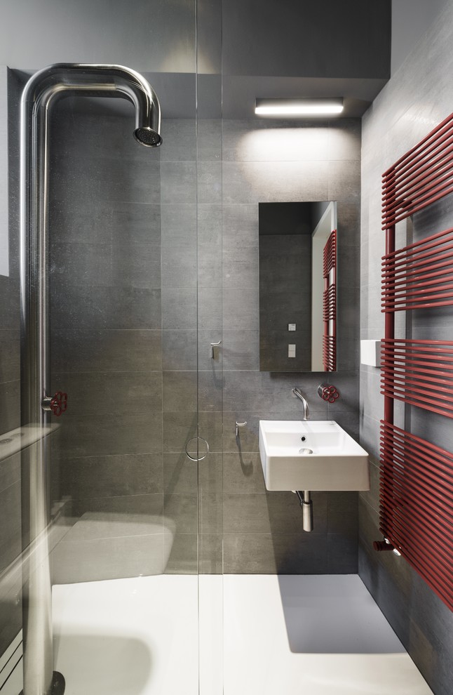 Cette image montre une petite salle de bain design avec un carrelage gris, sol en béton ciré, un mur gris, un lavabo suspendu et un sol blanc.