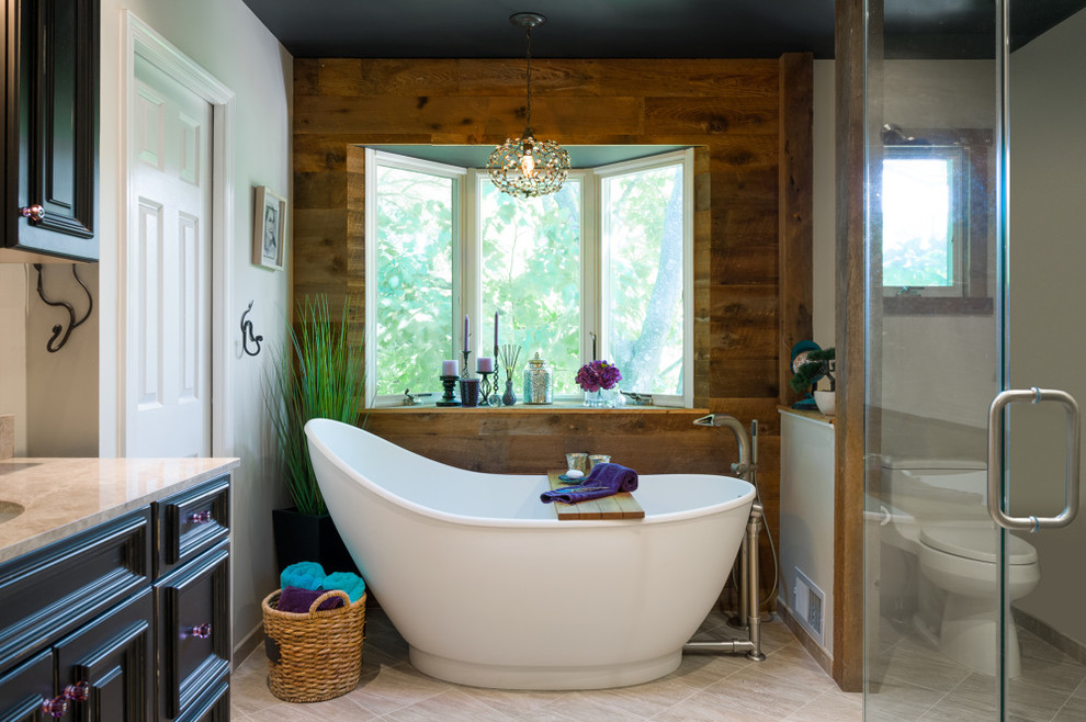 Foto de cuarto de baño principal rural con puertas de armario negras, bañera exenta, paredes beige, suelo de baldosas de porcelana y encimera de granito
