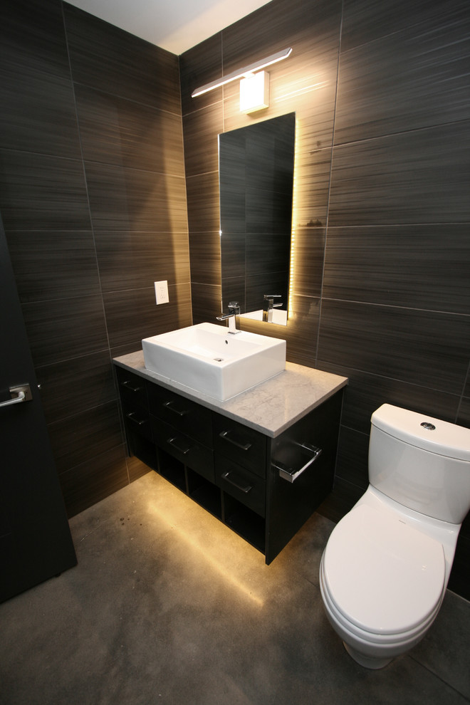 Foto på ett mellanstort funkis vit badrum med dusch, med släta luckor, svarta skåp, en dusch i en alkov, en toalettstol med hel cisternkåpa, svart kakel, porslinskakel, grå väggar, betonggolv, ett fristående handfat, bänkskiva i kvarts, grått golv och dusch med gångjärnsdörr