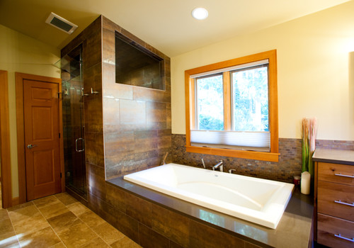 Imagen de cuarto de baño principal clásico renovado de tamaño medio con armarios con paneles lisos, puertas de armario de madera oscura, bañera encastrada, baldosas y/o azulejos marrones y paredes beige