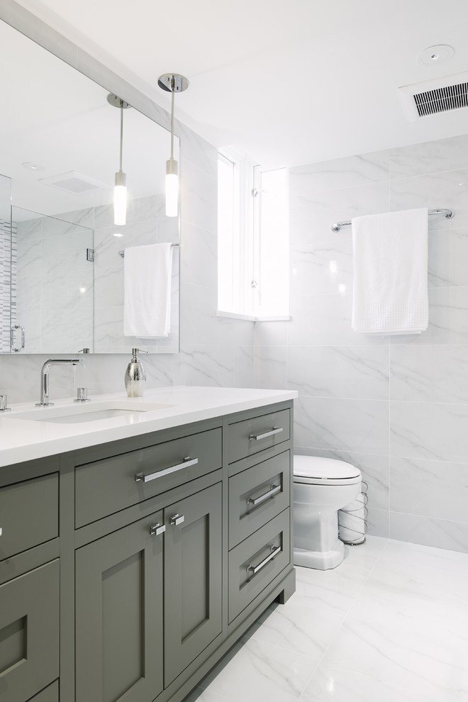 Inspiration pour une salle de bain principale traditionnelle de taille moyenne avec un placard à porte shaker, des portes de placard grises, des carreaux de porcelaine, un mur blanc, un sol en carrelage de porcelaine, un plan de toilette en quartz modifié, un lavabo encastré et un carrelage blanc.