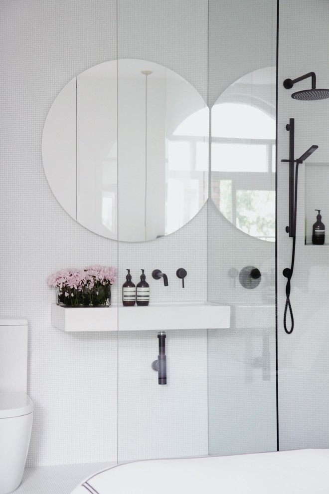 Modelo de cuarto de baño contemporáneo con bañera exenta, ducha a ras de suelo, sanitario de una pieza, baldosas y/o azulejos blancos, baldosas y/o azulejos en mosaico, paredes blancas, lavabo suspendido, suelo gris, ducha abierta y encimeras blancas