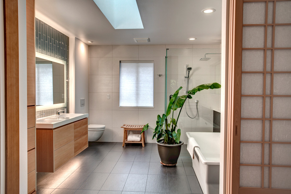 Idée de décoration pour une salle de bain design en bois brun avec un placard à porte plane, une baignoire indépendante, une douche d'angle, WC suspendus, un carrelage gris, un plan vasque, un sol gris, une cabine de douche à porte battante, meuble double vasque et meuble-lavabo suspendu.