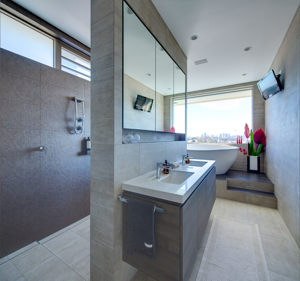 На фото: главная ванная комната в современном стиле с плоскими фасадами, серыми фасадами, отдельно стоящей ванной, серой плиткой, врезной раковиной, серым полом и белой столешницей