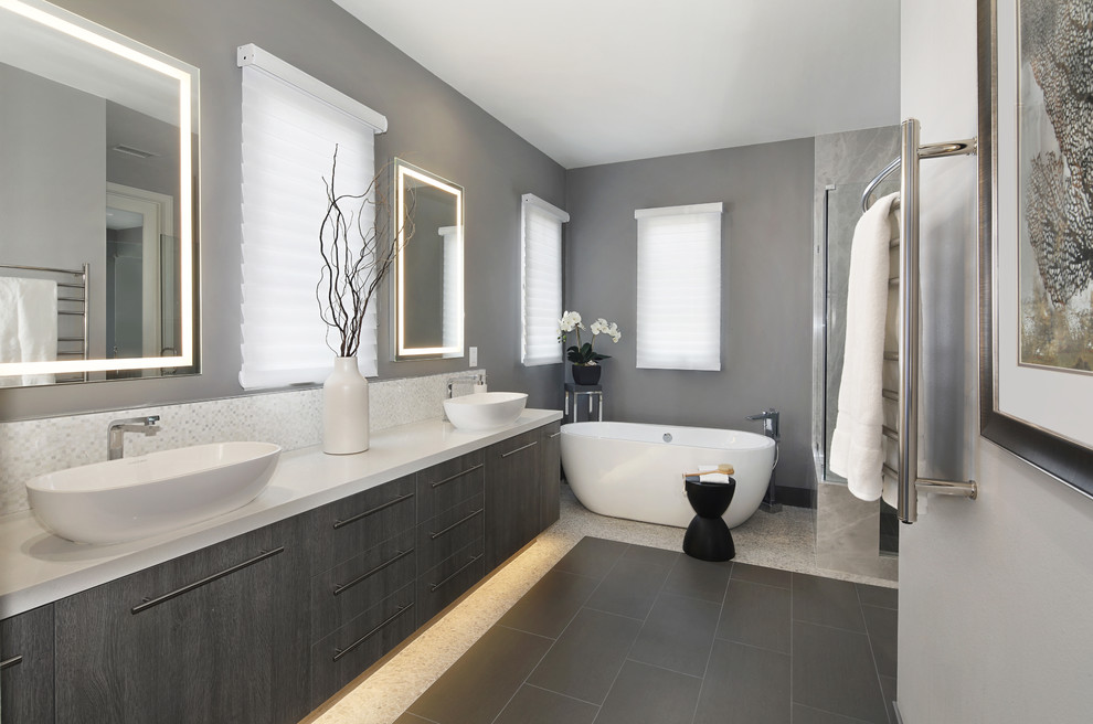 Idéer för ett mellanstort modernt vit en-suite badrum, med släta luckor, skåp i mörkt trä, ett fristående badkar, en hörndusch, grå kakel, stenhäll, grå väggar, klinkergolv i porslin, ett fristående handfat, bänkskiva i kvarts, grått golv och dusch med gångjärnsdörr