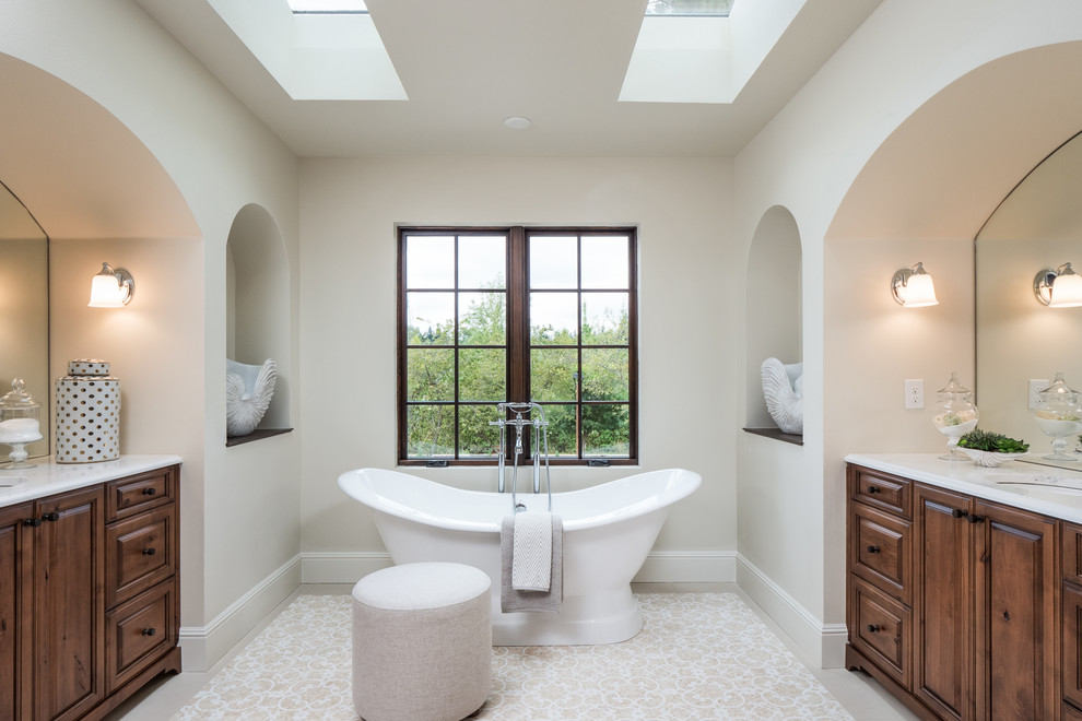 Immagine di una stanza da bagno padronale tradizionale con ante con bugna sagomata, ante in legno bruno, vasca freestanding, pareti grigie, lavabo sottopiano e pavimento beige