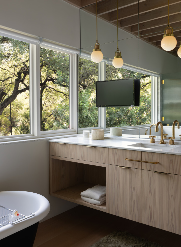 Inspiration for a medium sized contemporary ensuite bathroom in Austin with flat-panel cabinets, beige cabinets, a freestanding bath, white walls, medium hardwood flooring, a submerged sink, brown floors and white worktops.