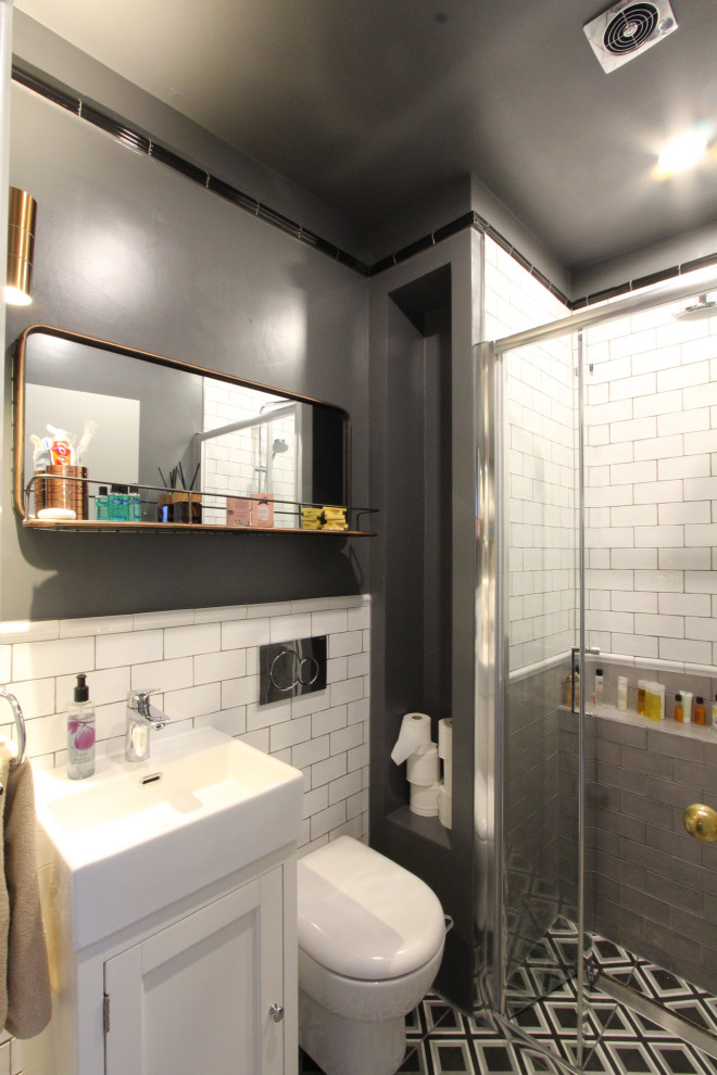 Modern inredning av ett litet en-suite badrum, med luckor med infälld panel, ett platsbyggt badkar, en kantlös dusch, grå kakel, porslinskakel, grå väggar och svart golv