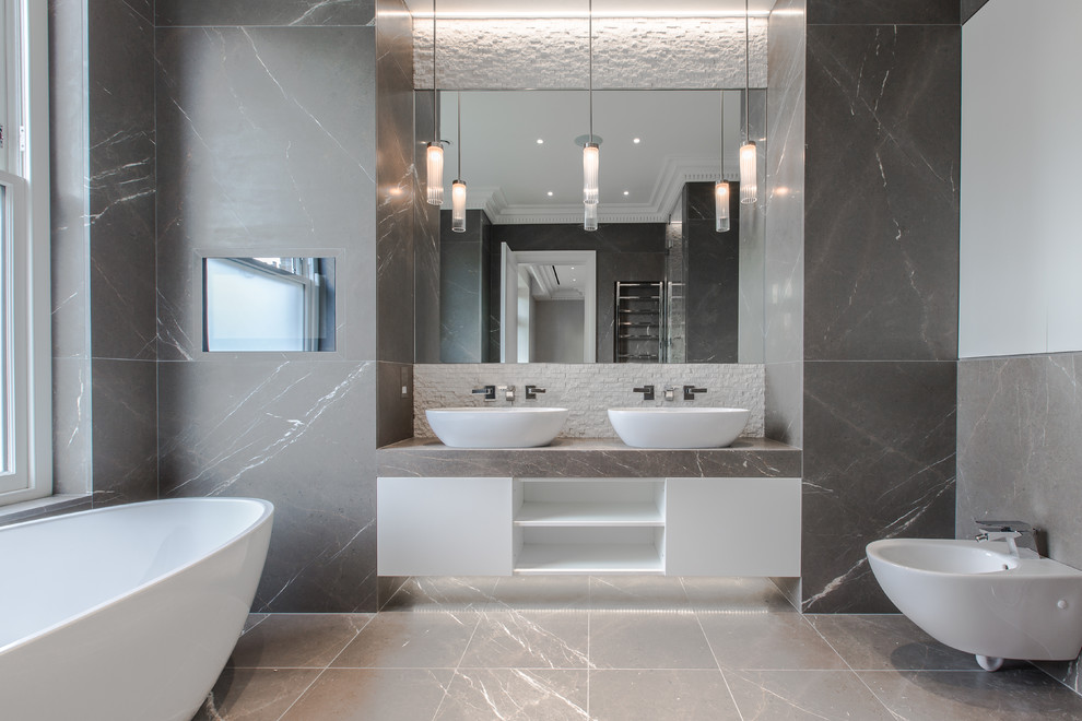 Foto på ett funkis grå badrum, med vita skåp, ett fristående badkar, grå väggar, marmorgolv, marmorbänkskiva och grått golv