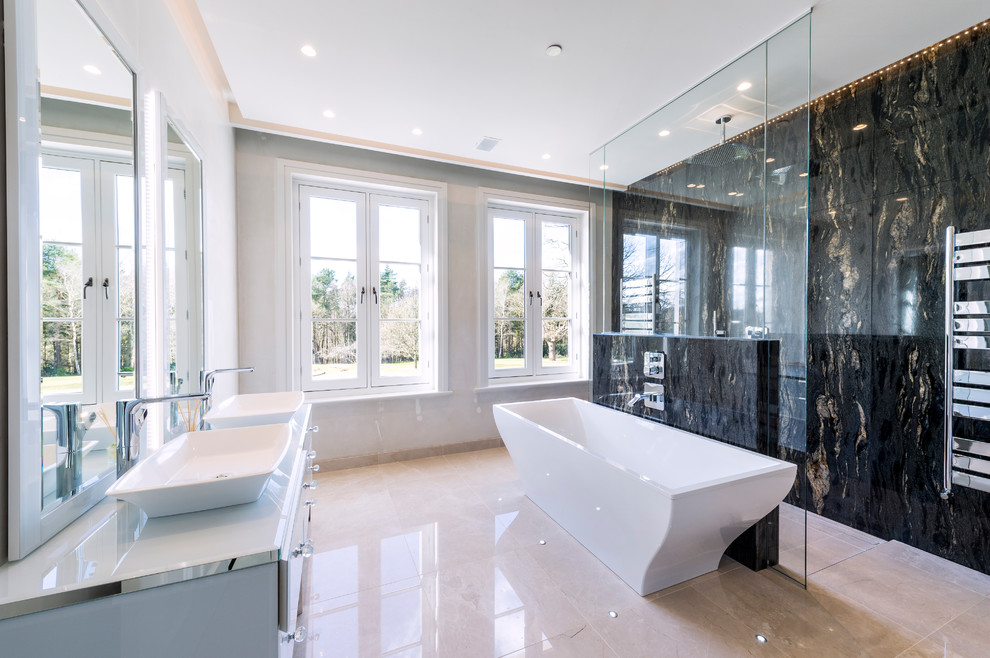 На фото: главная ванная комната в современном стиле с отдельно стоящей ванной, душевой комнатой, черной плиткой, серыми стенами, настольной раковиной, бежевым полом, открытым душем и белой столешницей