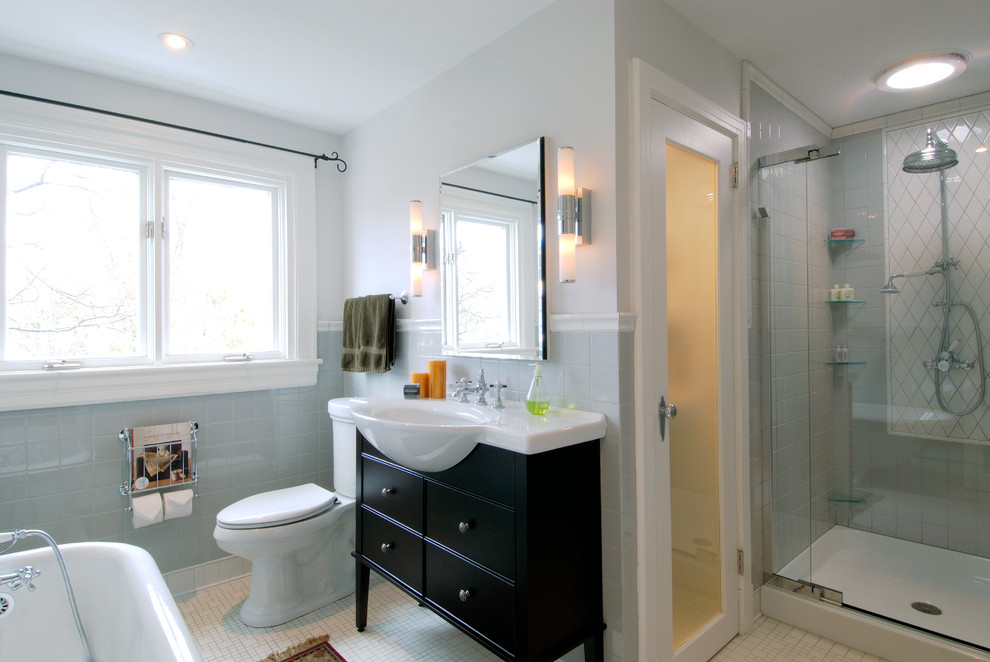 Photo of a traditional bathroom in Ottawa with a console sink, freestanding cabinets, dark wood cabinets, a claw-foot bath, an alcove shower, a two-piece toilet, white tiles and stone slabs.
