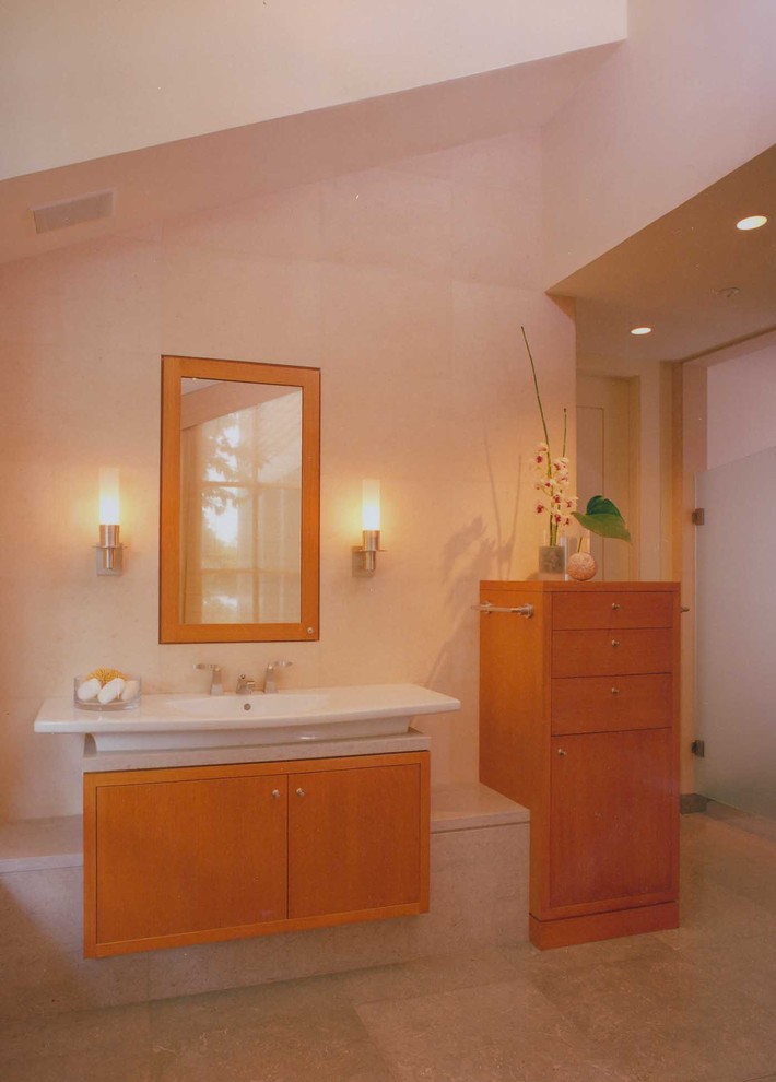 Inredning av ett modernt stort en-suite badrum, med ett undermonterad handfat, släta luckor, skåp i ljust trä, bänkskiva i kalksten, ett undermonterat badkar, en kantlös dusch, en toalettstol med hel cisternkåpa, grå kakel, stenkakel, beige väggar och kalkstensgolv