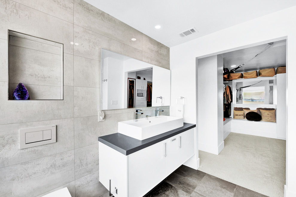 Свежая идея для дизайна: главная ванная комната среднего размера в современном стиле с плоскими фасадами, белыми фасадами, ванной в нише, двойным душем, инсталляцией, белой плиткой, керамической плиткой, белыми стенами, полом из керамогранита, монолитной раковиной, столешницей из бетона, коричневым полом, душем с распашными дверями и черной столешницей - отличное фото интерьера