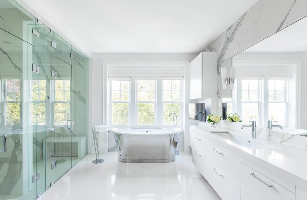 This is an example of a large contemporary ensuite wet room bathroom in Toronto with flat-panel cabinets, white cabinets, a freestanding bath, white walls, white floors, a hinged door, grey tiles, white tiles, marble tiles, a submerged sink and solid surface worktops.
