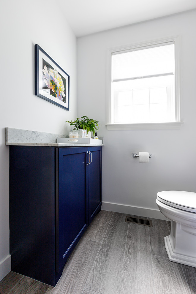 Exemple d'une salle de bain principale chic de taille moyenne avec un placard avec porte à panneau encastré, des portes de placard bleues, une douche ouverte, WC à poser, un carrelage gris, des carreaux de céramique, un mur gris, un lavabo posé, un plan de toilette en marbre, une cabine de douche à porte battante et un plan de toilette blanc.