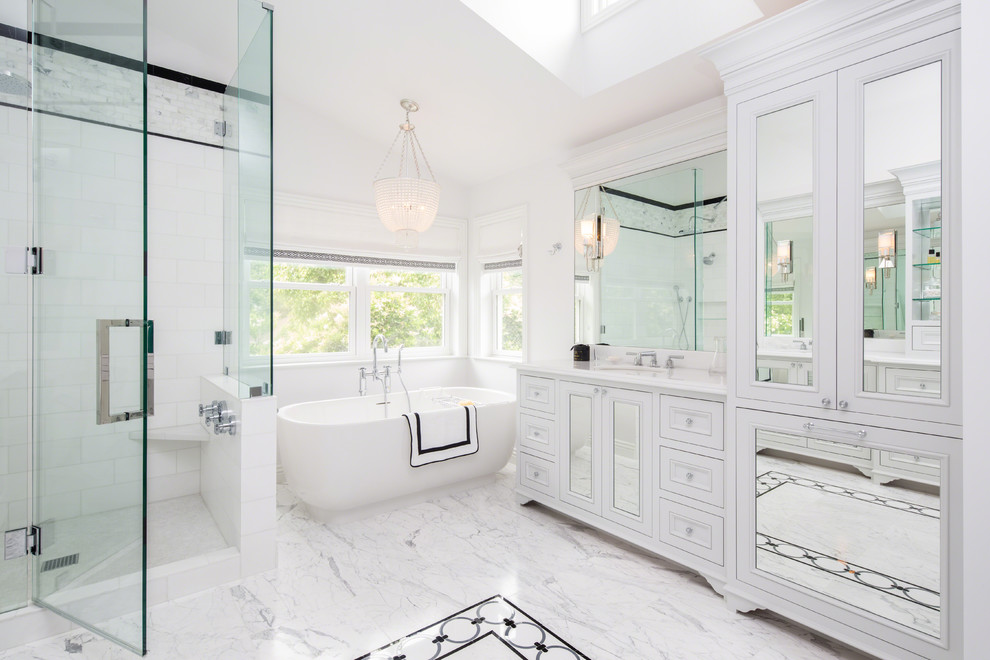 Источник вдохновения для домашнего уюта: ванная комната в классическом стиле с фасадами с утопленной филенкой, белыми фасадами, отдельно стоящей ванной, угловым душем, белыми стенами, мраморным полом, врезной раковиной и душем с распашными дверями