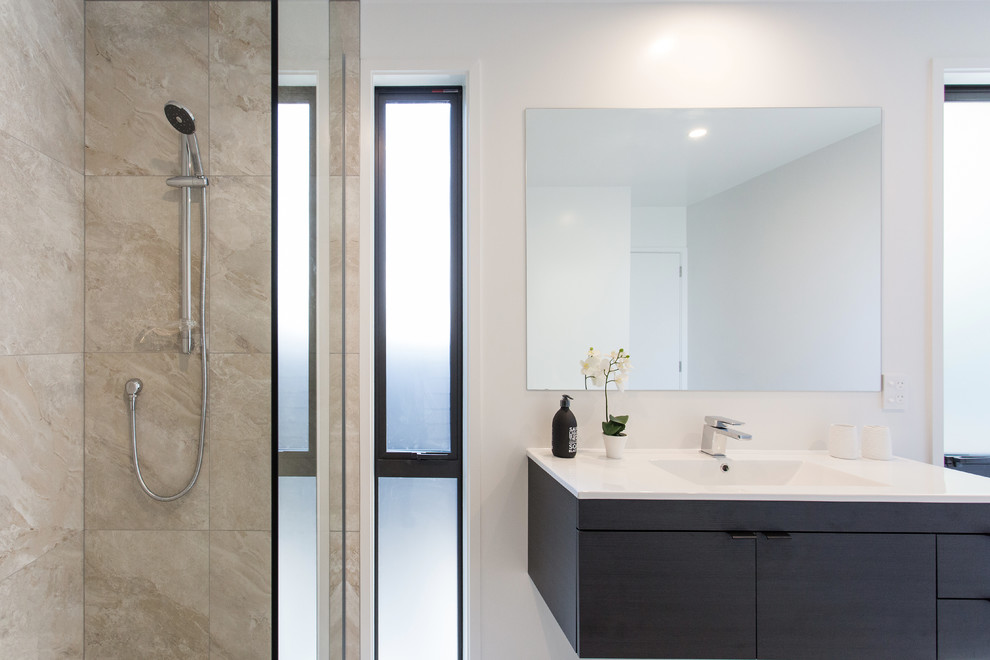Modern ensuite bathroom in Christchurch with a walk-in shower, a one-piece toilet, beige tiles, ceramic tiles, white walls, ceramic flooring, a built-in sink, beige floors and an open shower.