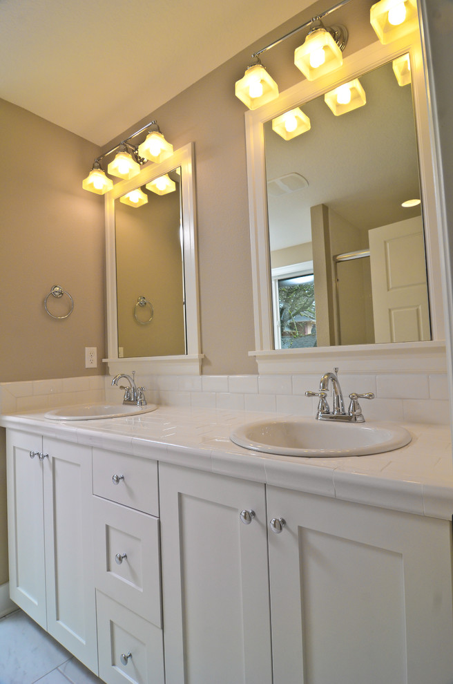 Example of a mid-sized classic white tile ceramic tile bathroom design in Portland with a drop-in sink, recessed-panel cabinets, white cabinets, tile countertops, a one-piece toilet and beige walls