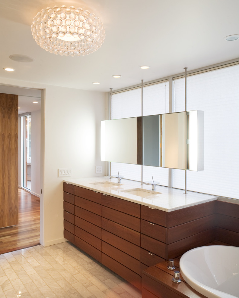 Idée de décoration pour une salle de bain minimaliste en bois foncé avec un lavabo encastré, un placard à porte plane, une baignoire posée et un carrelage beige.