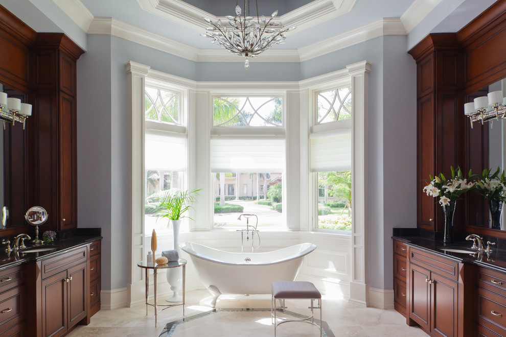 Идея дизайна: большая главная ванная комната в классическом стиле с фасадами с утопленной филенкой, фасадами цвета дерева среднего тона, столешницей из гранита, отдельно стоящей ванной, синими стенами и мраморным полом