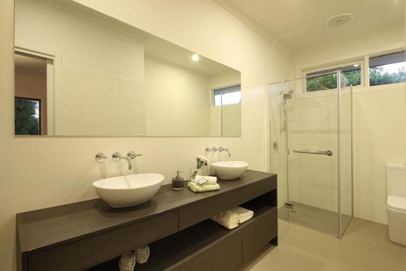 Ejemplo de cuarto de baño actual grande con lavabo sobreencimera, ducha esquinera, sanitario de una pieza, baldosas y/o azulejos beige y paredes blancas