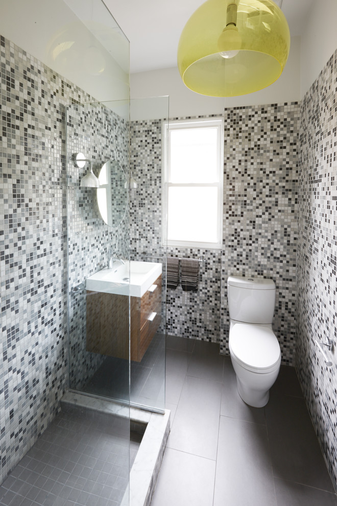 Idéer för ett litet modernt badrum, med ett väggmonterat handfat, släta luckor, skåp i mellenmörkt trä, bänkskiva i akrylsten, en öppen dusch, en toalettstol med hel cisternkåpa, flerfärgad kakel, keramikplattor, grå väggar, klinkergolv i porslin och med dusch som är öppen