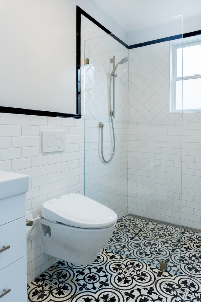 Cette image montre une petite salle d'eau design avec un placard en trompe-l'oeil, des portes de placard blanches, une douche ouverte, WC à poser, un carrelage noir et blanc, des plaques de verre, un mur blanc, un sol en carrelage de céramique et un lavabo posé.