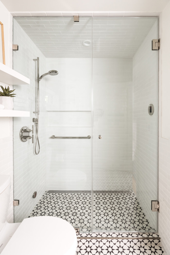 Idée de décoration pour une salle de bain design avec WC à poser, un carrelage blanc, un carrelage métro, un mur blanc, un sol en carrelage de céramique, un sol blanc, une cabine de douche à porte battante et du carrelage bicolore.