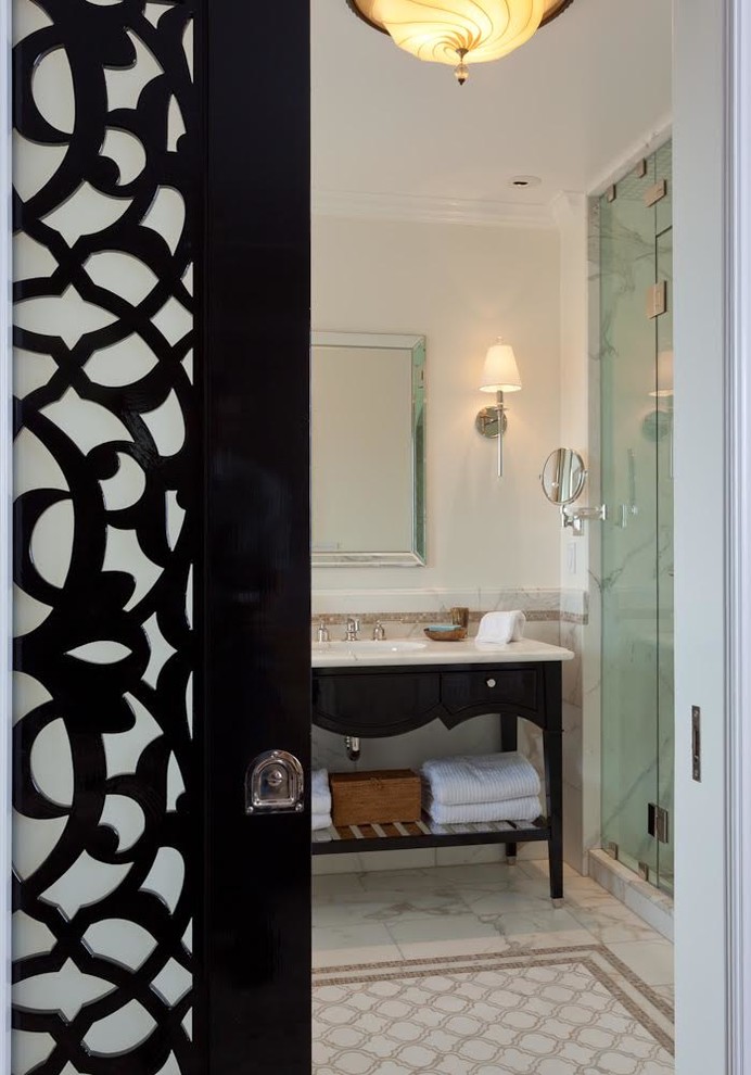 Ispirazione per una stanza da bagno padronale mediterranea con consolle stile comò, ante nere, vasca freestanding, piastrelle beige, piastrelle di vetro, pareti beige, lavabo sottopiano e top in marmo