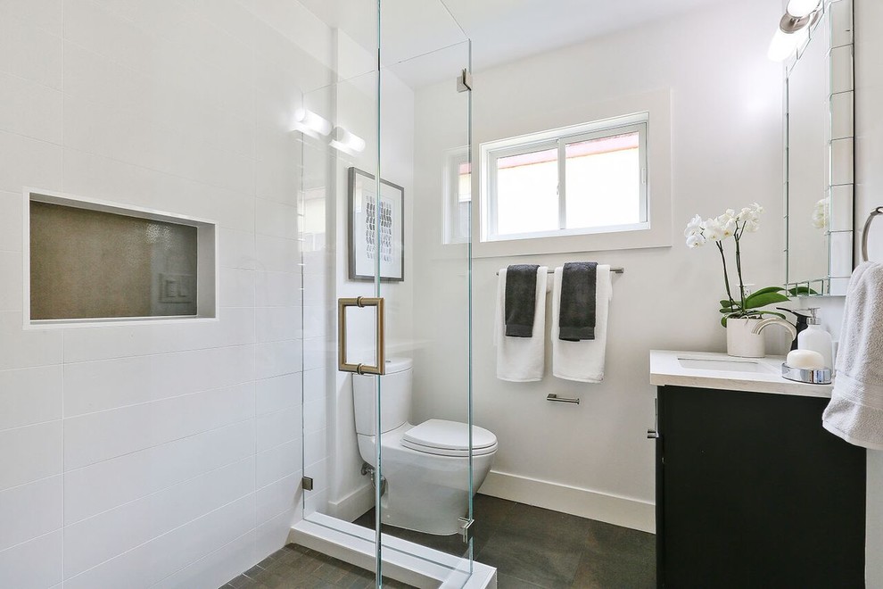 Idées déco pour une petite salle d'eau moderne avec des portes de placard noires, une douche d'angle, WC à poser, un carrelage gris, un carrelage blanc, des carreaux de céramique, un mur gris, un sol en ardoise, un lavabo encastré, un plan de toilette en quartz modifié, un sol gris, une cabine de douche à porte battante et un plan de toilette blanc.
