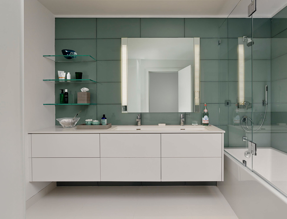 Exempel på ett mellanstort modernt en-suite badrum, med släta luckor, vita skåp, ett badkar i en alkov, en dusch/badkar-kombination, grå kakel, grön kakel, glaskakel, ett avlångt handfat, gröna väggar, klinkergolv i porslin och bänkskiva i akrylsten