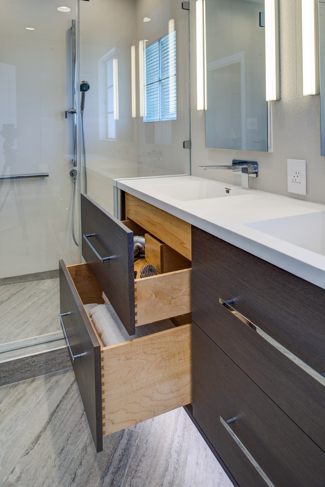 Medium sized modern ensuite bathroom in San Francisco with an integrated sink, flat-panel cabinets, dark wood cabinets, solid surface worktops, an alcove shower, a wall mounted toilet, grey tiles, porcelain tiles, grey walls, porcelain flooring, grey floors, a hinged door, white worktops, a wall niche, double sinks and a floating vanity unit.