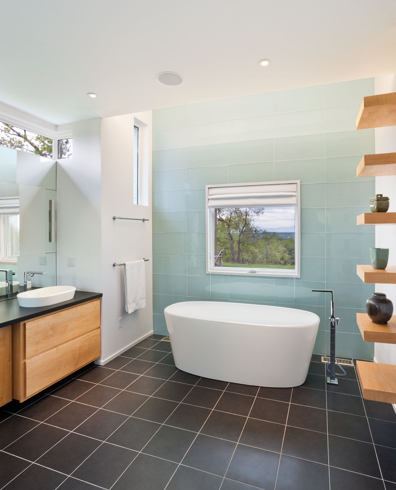 Ejemplo de cuarto de baño actual con bañera exenta, lavabo sobreencimera y baldosas y/o azulejos de vidrio