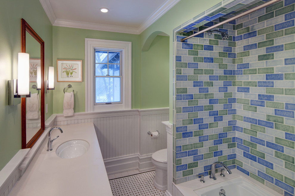 Exemple d'une salle de bain chic en bois foncé de taille moyenne pour enfant avec un lavabo encastré, un placard avec porte à panneau surélevé, un plan de toilette en surface solide, une baignoire encastrée, un combiné douche/baignoire, WC séparés, un carrelage bleu, mosaïque, un mur vert, un sol en carrelage de porcelaine, un sol multicolore et une cabine de douche avec un rideau.