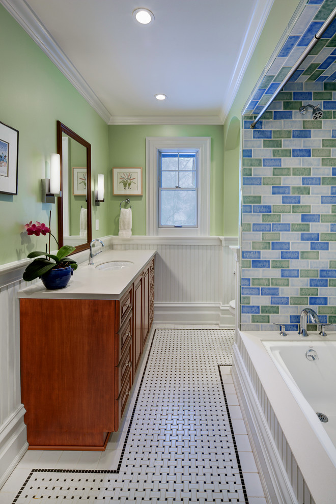 На фото: детская ванная комната среднего размера в стиле неоклассика (современная классика) с врезной раковиной, фасадами с выступающей филенкой, темными деревянными фасадами, столешницей из искусственного камня, полновстраиваемой ванной, душем над ванной, унитазом-моноблоком, зеленой плиткой, плиткой кабанчик, зелеными стенами и полом из керамогранита