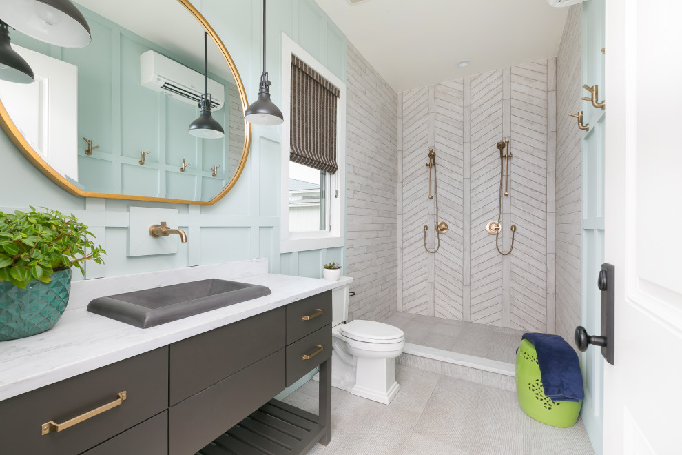 Exemple d'une salle d'eau bord de mer avec un placard à porte plane, des portes de placard grises, une douche double, un carrelage gris, un mur bleu, un sol gris et un plan de toilette blanc.
