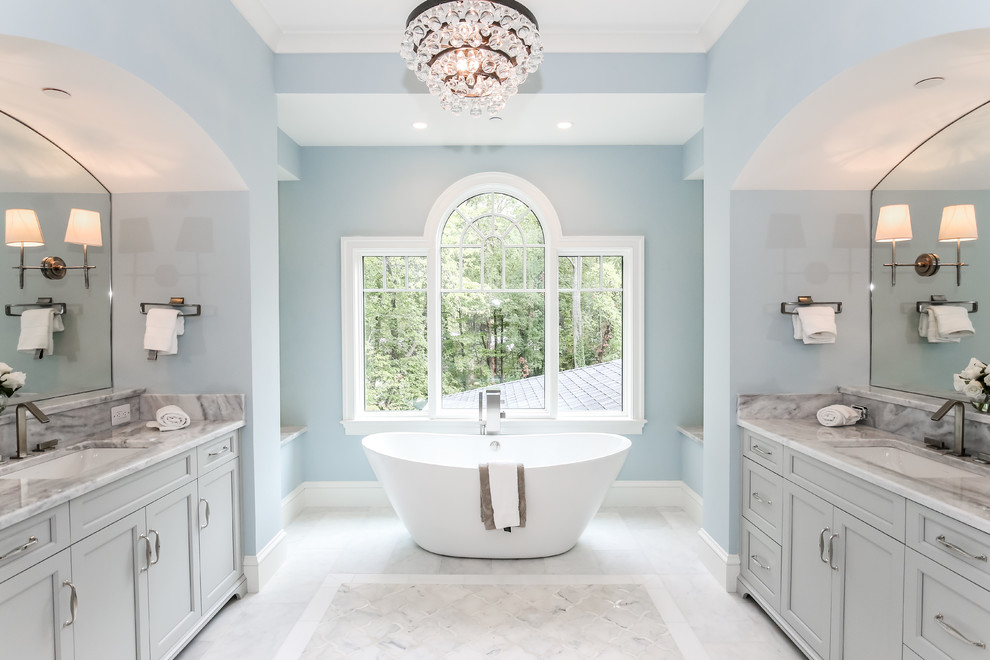Foto de cuarto de baño principal y rectangular tradicional con lavabo bajoencimera, armarios con paneles empotrados, puertas de armario grises, bañera exenta y paredes azules