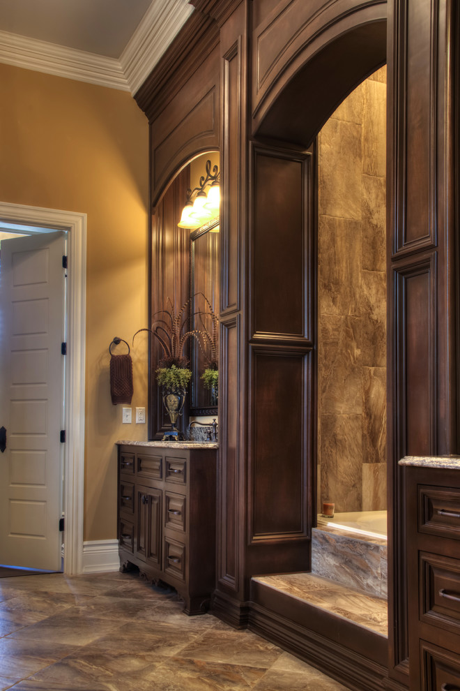 Example of a classic master brown tile and porcelain tile porcelain tile bathroom design in Other with furniture-like cabinets, dark wood cabinets, granite countertops, a one-piece toilet, an undermount sink and brown walls