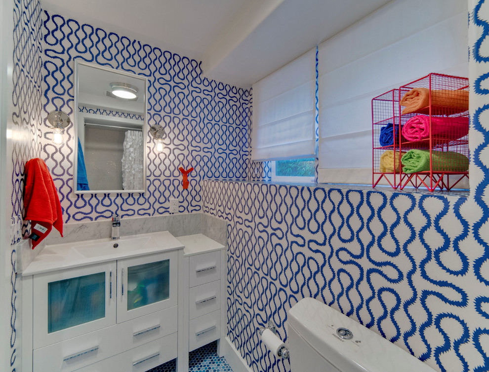 Idéer för att renovera ett litet funkis badrum för barn, med ett integrerad handfat, luckor med glaspanel, vita skåp, bänkskiva i akrylsten, en toalettstol med hel cisternkåpa, blå väggar, mosaikgolv, en dusch i en alkov, blå kakel och porslinskakel