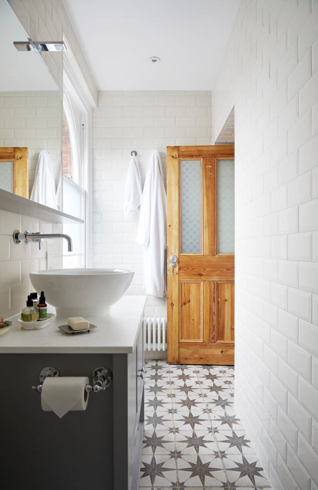Свежая идея для дизайна: ванная комната среднего размера в стиле кантри с плоскими фасадами, серыми фасадами, душевой комнатой, раздельным унитазом, бежевой плиткой, керамической плиткой, полом из терракотовой плитки, душевой кабиной, подвесной раковиной, мраморной столешницей, разноцветным полом, душем с распашными дверями, разноцветной столешницей, тумбой под одну раковину, напольной тумбой и кирпичными стенами - отличное фото интерьера